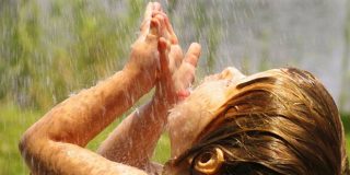 Παιδί προσπαθεί να δροσιστεί από σταγόνες νερού που πέφτουν - Πίνακας με τις ημερήσιες ανάγκες σε νερό για παιδιά