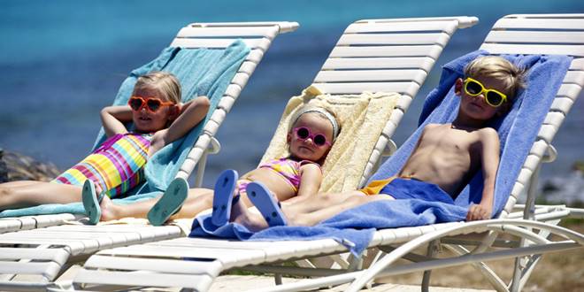 Παιδιά σε ξαπλώστρες στην παραλία απολαμβάνουν ήλιο και θάλασσα - Ηλίαση, συμπτώματα, συμβουλές και τρόποι αντιμετώπισης