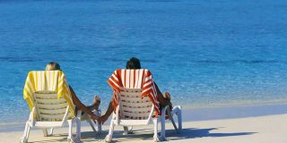 Ζευγάρι απολαμβάνει τις διακοπές του ξαπλωμένοι μπροστά στην θάλασσα ...μας υπενθυμίζουν την ψυχολογική σημασία των διακοπών