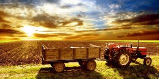 Τρακτέρ με ρυμουλκό σε αγροτεμάχιο κατά την δύση του ήλιου