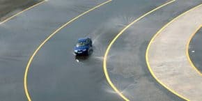 Οδήγηση αυτοκινήτου σε στροφή δρόμου - πίστας γεμάτη με νερό για test σε συμβουλές οδήγησης στη βροχή - Υδρολίσθηση