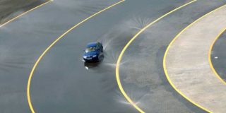 Οδήγηση αυτοκινήτου σε στροφή δρόμου - πίστας γεμάτη με νερό για test σε συμβουλές οδήγησης στη βροχή - Υδρολίσθηση