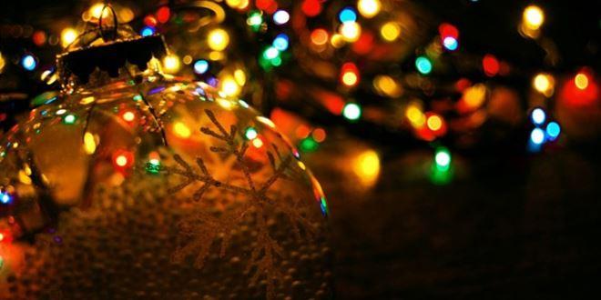 Χριστουγεννιάτικο γυάλινη μπάλα - στολίδι πάνω σε δέντρο με πολύχρωμα φωτάκια (λαμπιόνια) με γιορτινή ατμόσφαιρα