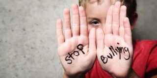 Μαθητής που έχει δεχθεί σχολικό εκφοβισμό, δείχνει παλάμες που γράφουν «Stop Bullying» | Συμβουλές ψυχολόγων για γονείς