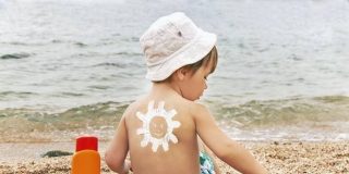 Παιδί στην θάλασσα απολαμβάνει το μπάνιο, προστατευμένο από την Ηλιακή ακτινοβολία ● Δελτίο πρόγνωσης και κλίμακα δείκτη UV