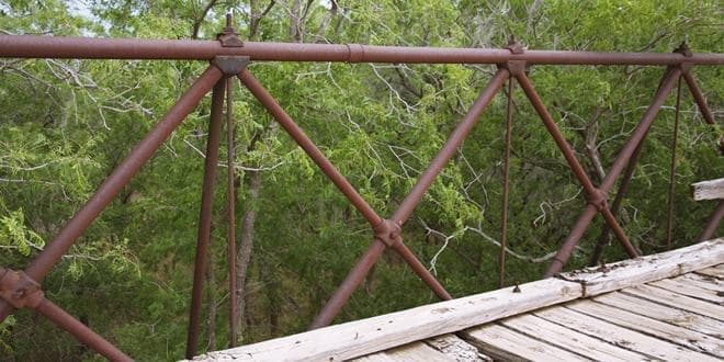 Μεταλλικά προστατευτικά κάγκελα γέφυρας σε δάσος, σχηματίζουν ένα γεωμετρικό ορθογώνιο παραλληλόγραμμο και τις διαγώνιες του