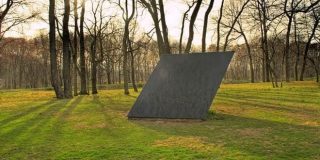 Γρανιτένια κατασκευή γλυπτό - μνημείο σε άλσος που παραπέμπει νοητά στο γεωμετρικό σχήμα Ρόμβος και στο εμβαδόν του